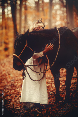 Shaman woman in autumn landscape with her horse.