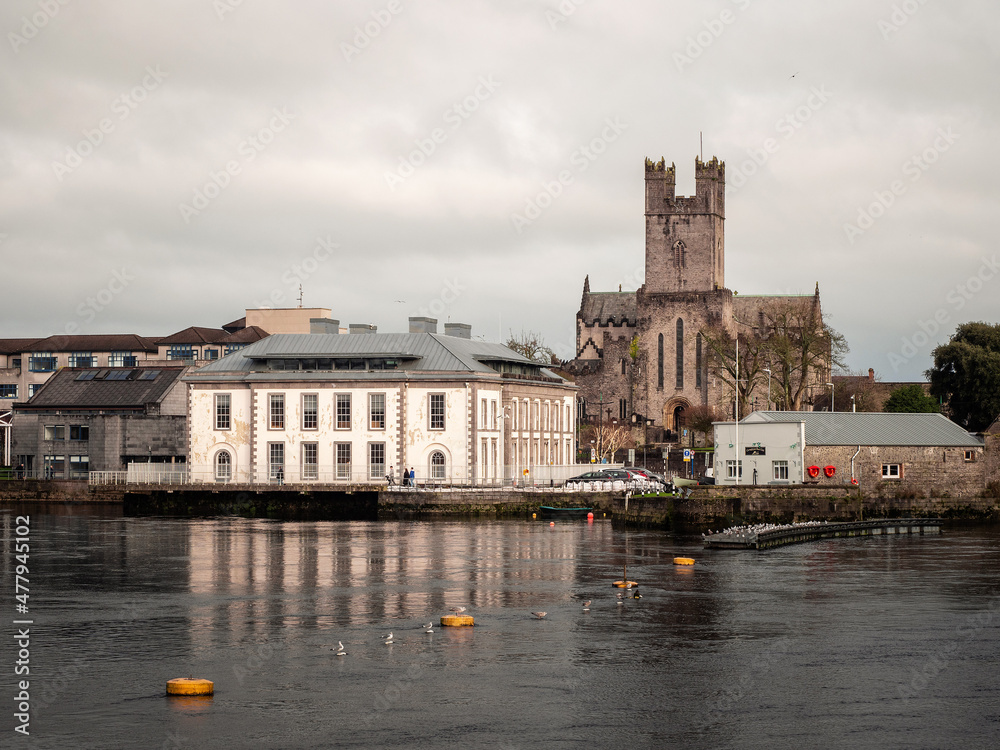 Limerick City District Court building and St Mary's Cathedral. Ireland. Reflection in river Shannon. Popular town landmark and tourist spot. Cloudy sky.