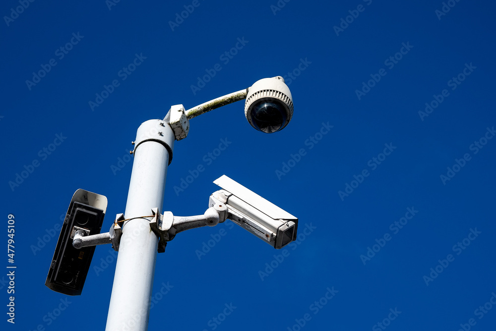 Outdoor security cameras on a metal pole against dark blue sky. Security industry. Government control and surveillance over their citizens concept. Outdoor security cameras on a metal pole against dark blue sky. Security industry. Government control and surveillance over their citizens concept.