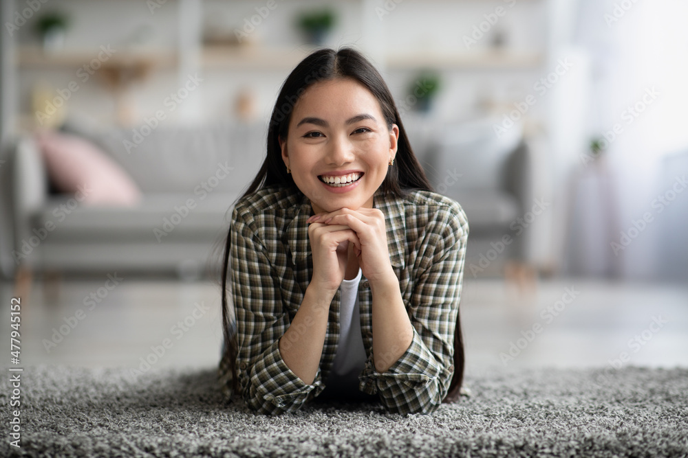 Relaxed fair hair asian woman laying on carpet at home