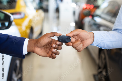 Black Male Customer Taking Car Keys From Seller In Dealership Center, Closeup