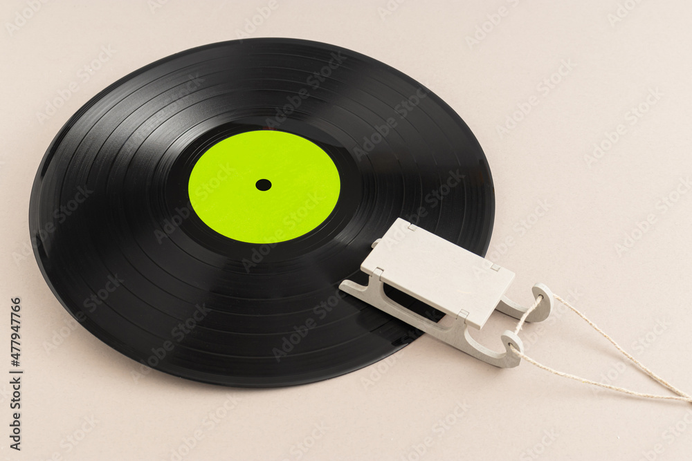 Fototapeta premium Minimal pop art holiday composition made with vinyl record with green label and sled against beige background. Creative retro music winter concept.