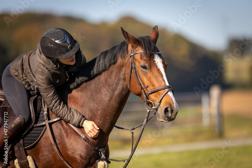 Horse in close-up with rider in the saddle, rider shows the horse her love.. © RD-Fotografie