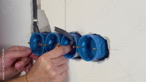 Installation of the socket in a wall with an electric wire. Exposed wire in the electrical wiring in the wall