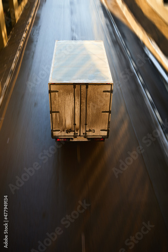 Cargo truck driving on a highway, aerial view. Back view of delivery van in motion. Dirty truck moving on the asphalt roadwith motion blur effect. photo