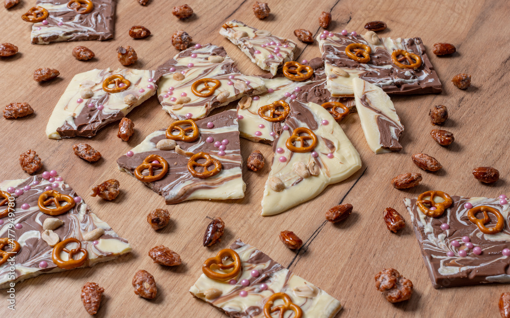 Weiße und braune Schokolade vorbereitet für eine Bruchschokolade dekoriert mit Brezel, Zucker Perlen und Nüssen