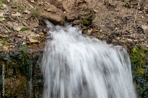 Millennial cold forest creek, little waterfalls over the rocks with slippery moss