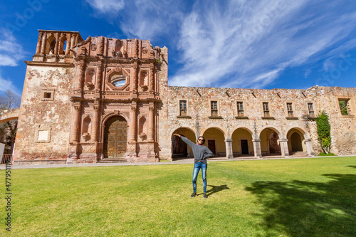 A young adult woman exhibits the facade of a very important museum in the city of Zacatecas in Mexico photo
