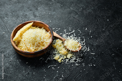 Grated parmesan cheese in a bowl. Cheese. Top view. On a stone background.