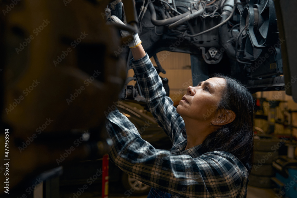 Focused repair shop worker being absorberd in car diagnostics
