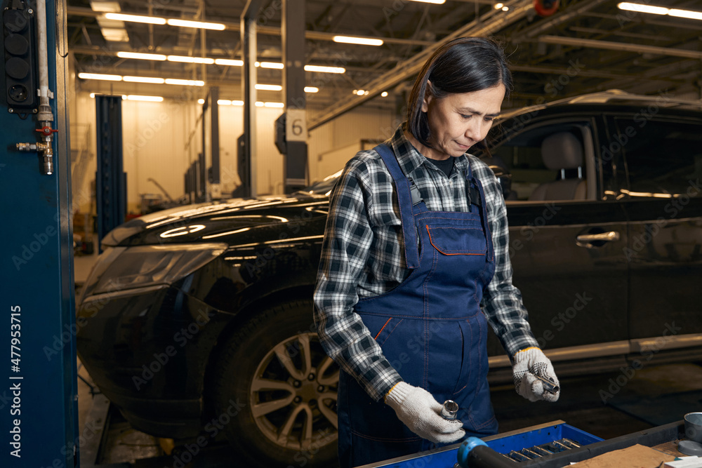 Serious female mechanic is holding different instruments Serious female mechanic is holding different instruments