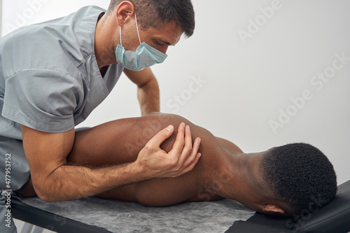 Focused qualified Caucasian doctor performing chiropractic adjustment photo