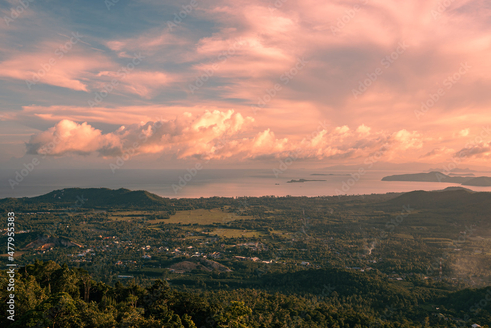 Panorama forest valley, mountains, village, sea and islands at sunset. Colorful clouds in the sky over tropical island. View from the top.