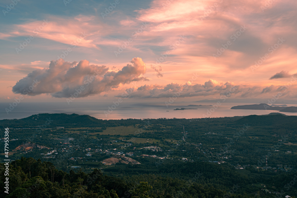 Panorama forest valley, mountains, village, sea and islands at sunset. Colorful clouds in the sky over tropical island. View from the top.