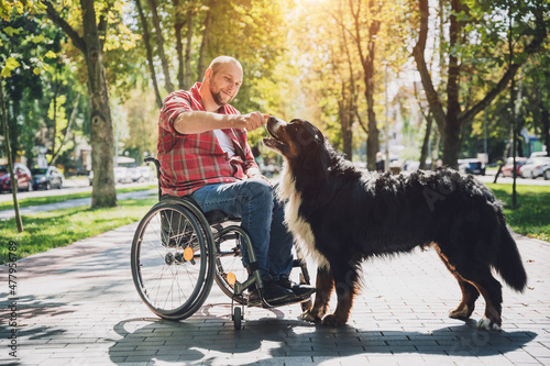 Happy young man with a physical disability who uses wheelchair with his dog. © romaset