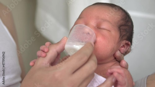 Father feeding milk with cup to him son baby. Asian man feeding milk kid infant. Relationship love family concept. 