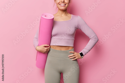 Фотография Cropped shot of unrecognizable sporty woman keeps hand on waist wears top and le