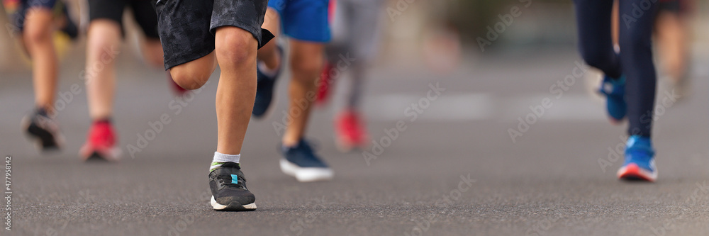 Running children, young athletes run in a kids run race,running on city road detail on legs,running in the light of morning