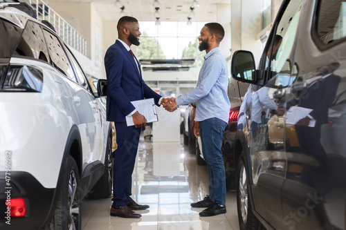 Black Car Seller Shaking Hands With Customer In Modern Dealership Center