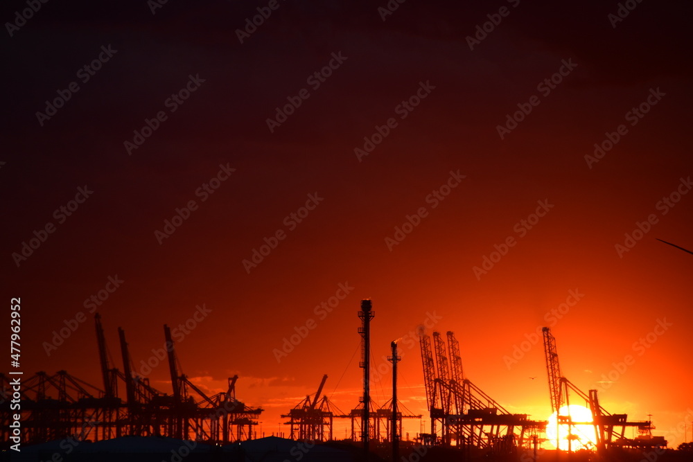 Dramatic sunset behind industrial port horizon