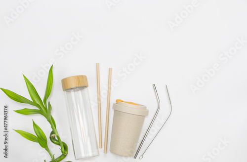 Reusable bamboo cup, glass bottle, stainless steel straws and paper.