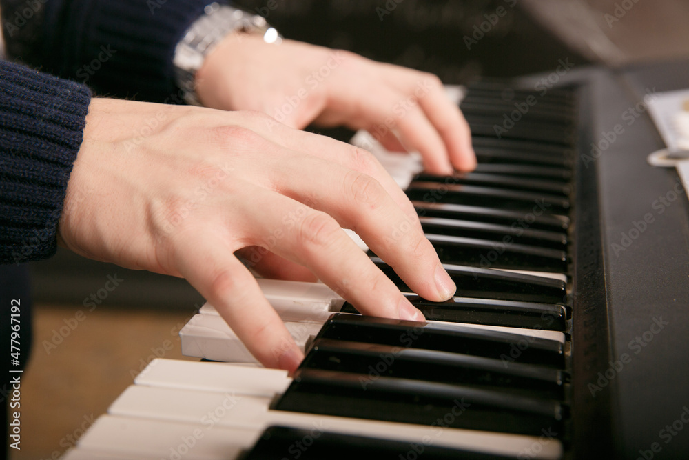 Fototapeta premium Hands of male musician playing at synthesizer. Mens arms plays solo of music or new melody. Close up fingers of pianist at the piano keys. Slow motion Top view.
