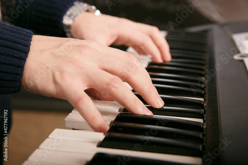 Hands of male musician playing at synthesizer. Mens arms plays solo of music or new melody. Close up fingers of pianist at the piano keys. Slow motion Top view.