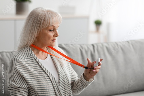 Senior woman holding and using Alarm Button, closeup photo
