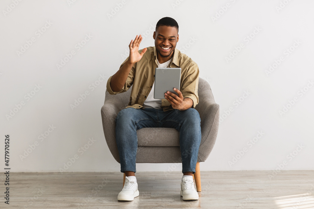 African Man Talking Video Calling Via Tablet Over Gray Wall African Man Talking Video Calling Via Tablet Over Gray Wall