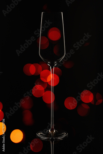 Still-life. The contour of a beautiful glass of thin glass for champagne against the background of festive lights 