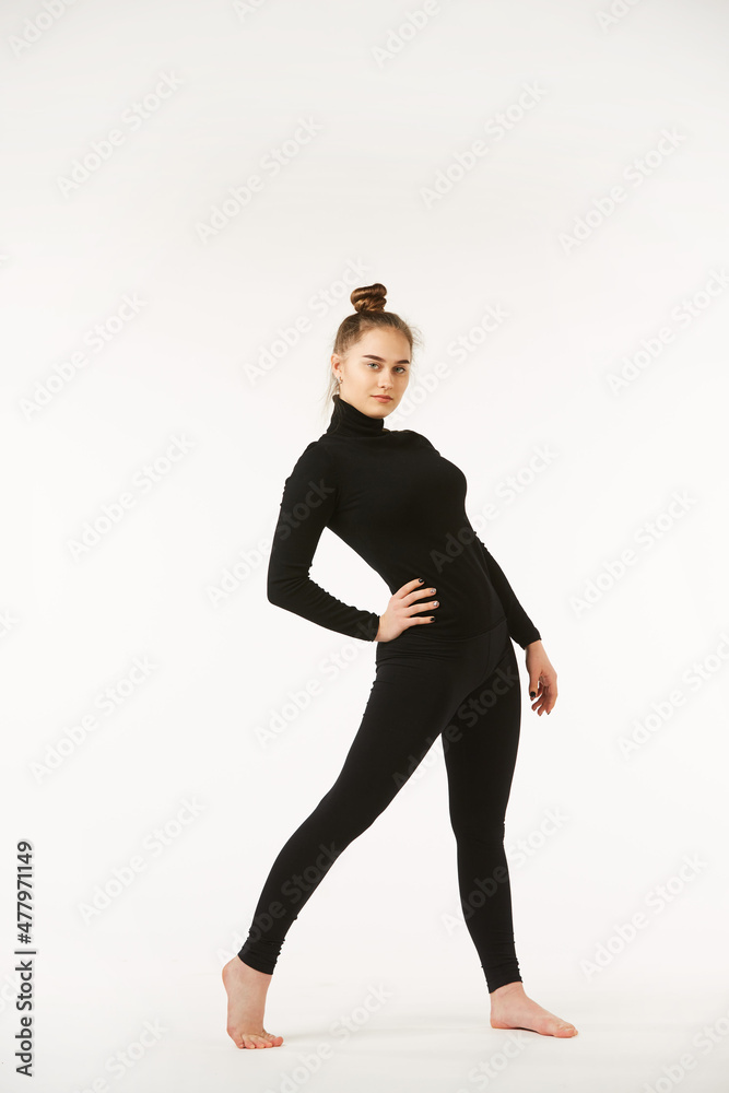 Obraz premium A girl in black clothes on a white isolated background performs dance and ballet poses and movements.