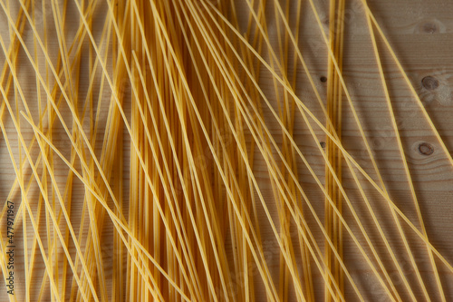 Fototapeta Naklejka Na Ścianę i Meble -  Yellow Spaghetti scattered on the table. Italian food concept. Spaghetti artistic background for publication, design, poster, calendar, post, screensaver, wallpaper, postcard, banner, cover, website