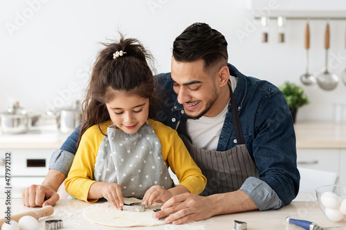 Loving arab dad and little daughter having fun together while baking in kitchen