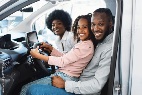Happy Afro family sitting in new car, going on test drive, buying automobile in dealership store