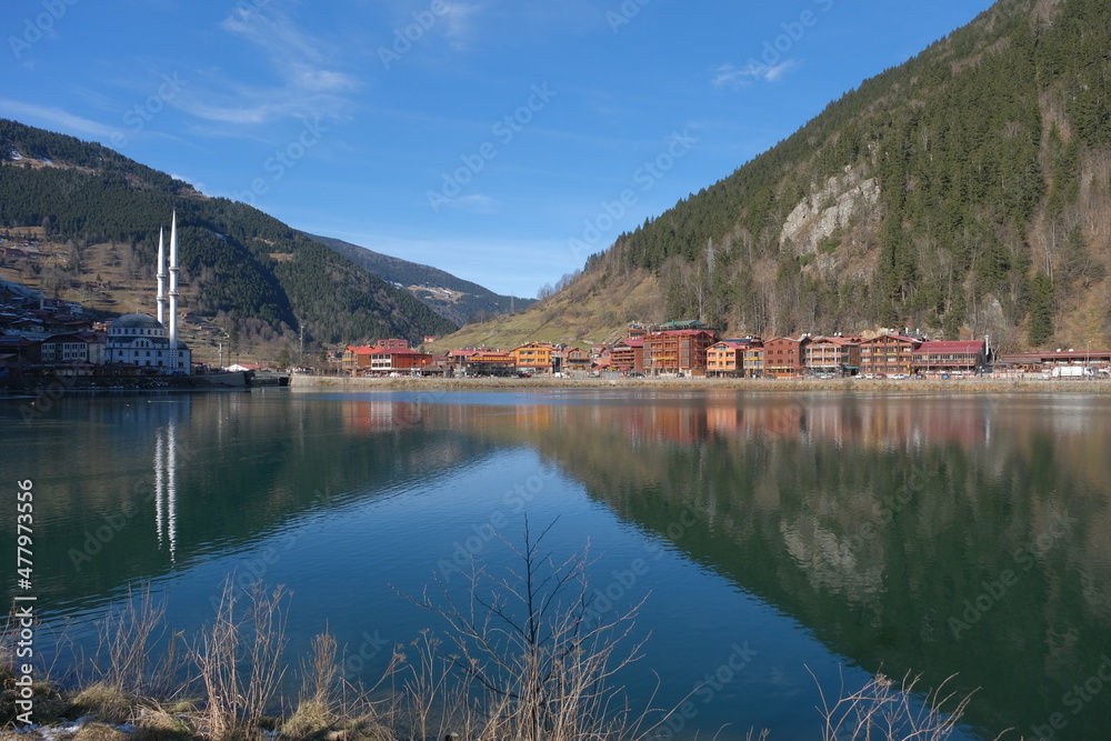 Fototapeta premium Local name is the lake is uzungol in Trabzon during winter. Snow at mountain peak, reflection of buildings on water.