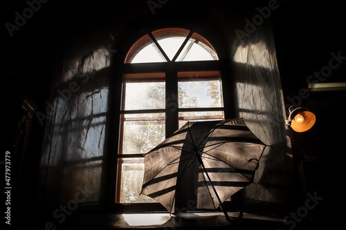 Black umbrella on a sill, near an old vintage window.