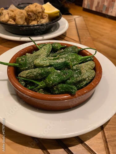 Fried and grilled padron peppers (Pimiento de padron, also known as pimiento de herbon) with sea salt. It is a famous Spanish tapas dish which originated from Galicia region. Plate of fried baby squid
