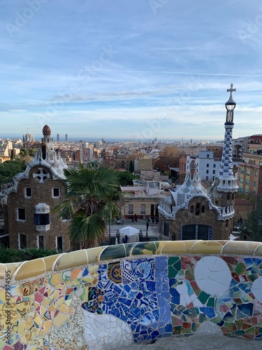 Famous colourful ceramic tiles benches at Park Guell. Panoramic view of the entrance. Skyline of Barcelona in the background. Unesco world heritage. Barcelona, Catalonia, Spain 