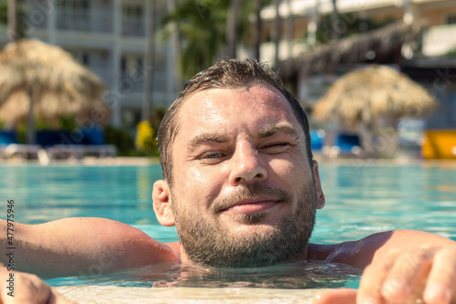 A smiling man relaxes in the hotel's swimming pool. © Barillo_Picture