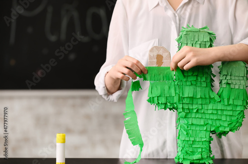 Woman making Mexican pinata in shape of cactus at table