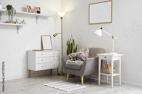 Interior of light living room with lamps  armchair and commode