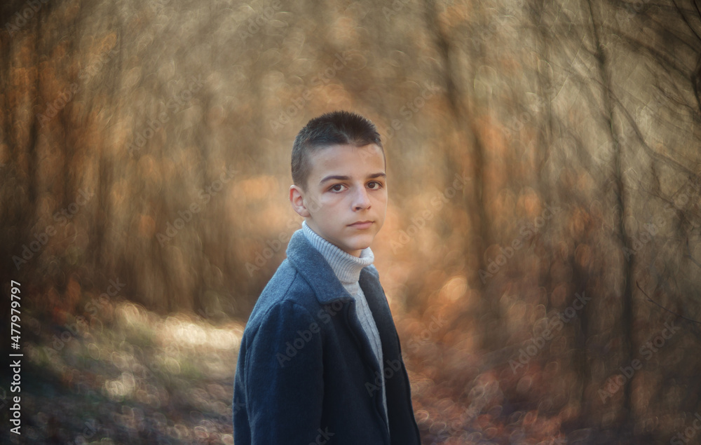 young teenager stands in the woods in late December