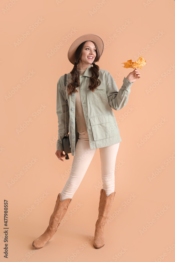 Obraz premium Elegant fashionable woman with autumn leaves on color background