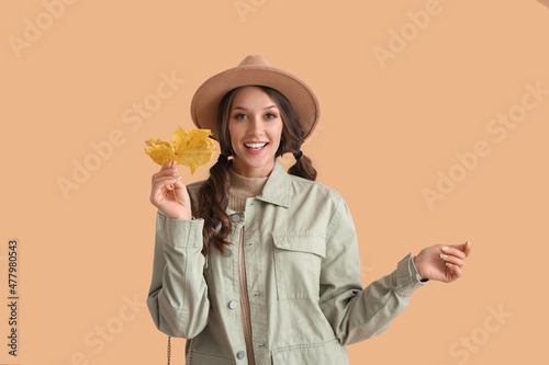 Happy woman with beautiful autumn leaf on color background