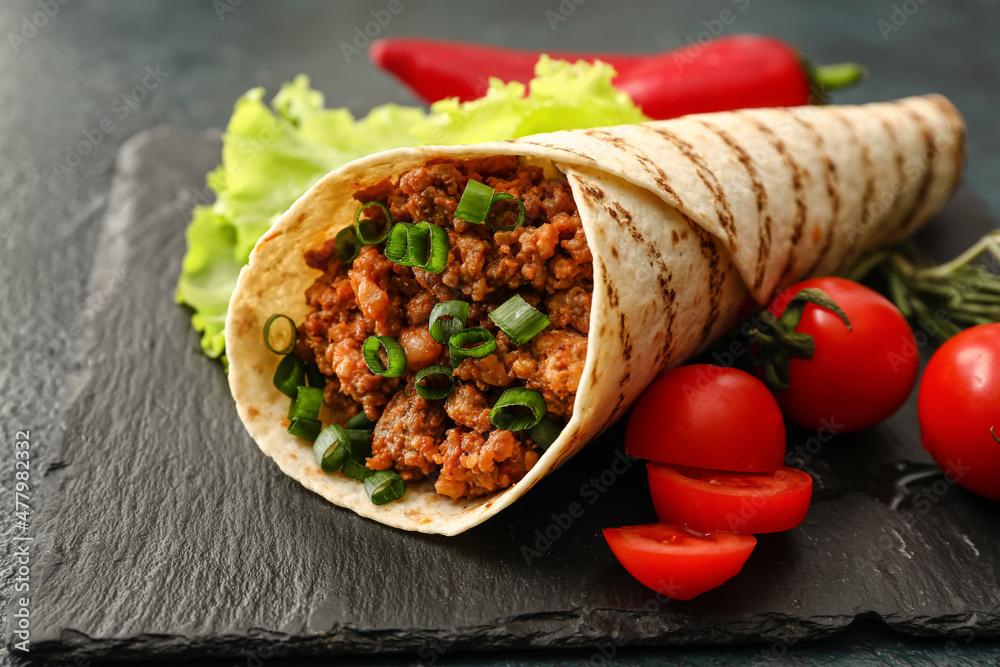 Slate plate with tasty burrito on dark background, closeup