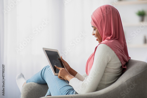 African Woman In Hijab Using Digital Tablet With Black Screen At Home