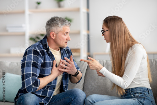 Irritated mature woman quarreling with her husband at home, being angry, experiencing family problems
