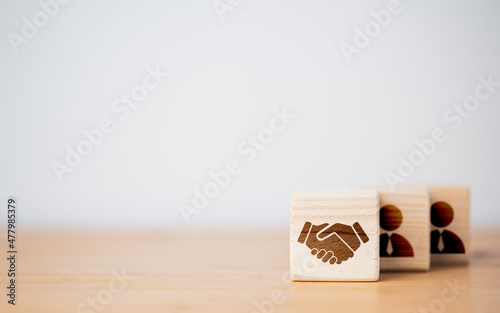 Hand shaking which print screen on wooden cube block  in front of human icon for business deal and agreement concept. photo