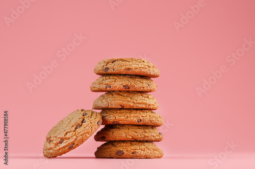 Oatmeal cookies with pieces of chocolate stand like a tower on a pink background