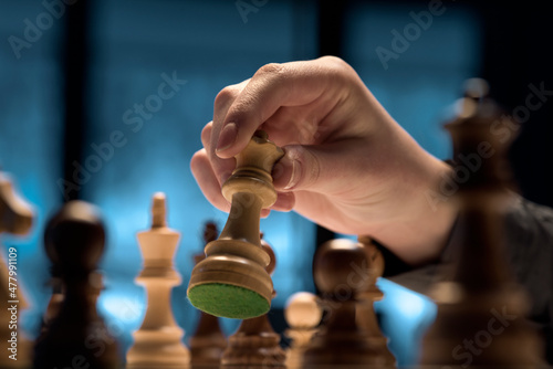 Man playing chess game and moving the queen